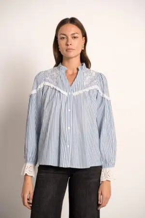 חולצה רפויה בצבע כחול עמוק, עם רקמה מורכבת על בד חלק, ככל הנראה כותנה, בגזרה רפויה.